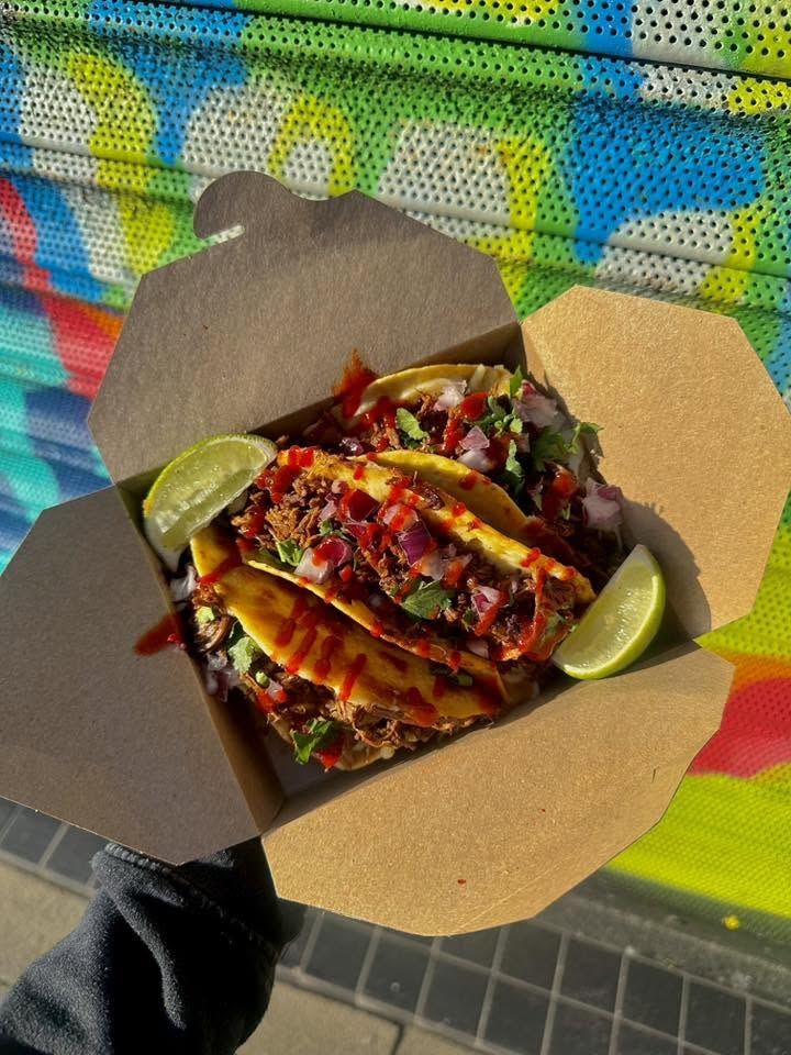 Loaded tacos with lime wedges in a takeaway box
