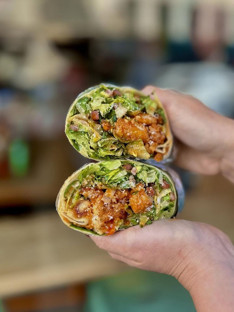 Close-up of a crispy chicken wrap with lettuce, sauce, and crispy filling